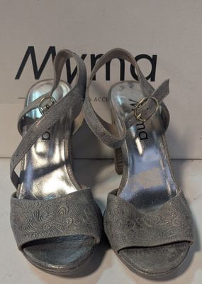 Les chaussures argentées de la femme se trouvent sur la boîte, à côté de celle-ci.