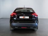 the rear end of a black car in a white room