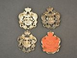 three silver and coral colored brooches with coats of arms