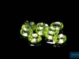 a close up of a group of green gems on a black surface