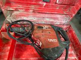 a red tool box with a drill and a cord in it