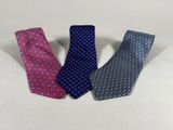 three different colored ties sitting next to each other on a white surface