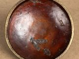 a wooden bowl with a metal rim sitting on a table
