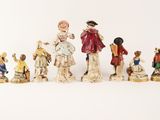 several figurines of people are standing in a line on a white surface