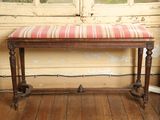 un banc avec un coussin rayé, placé devant une fenêtre