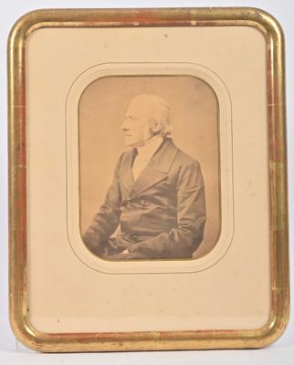 une vieille photo d'un homme en costume assis devant un fond blanc