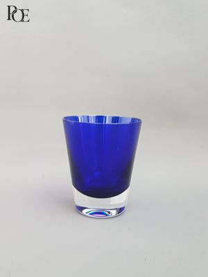 un verre bleu posé sur une surface blanche