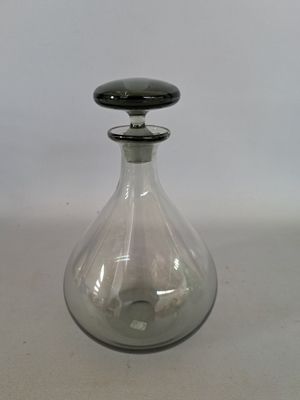 une bouteille en verre avec un bouchon noir posée sur une table