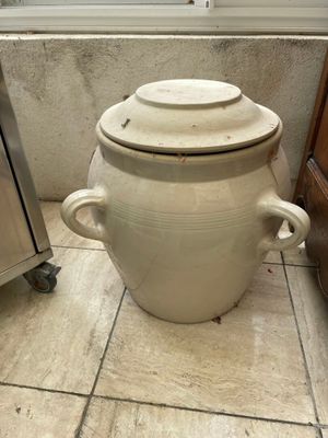 a large white pot sitting on the floor next to a stove