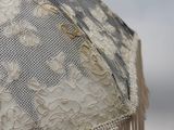 lace umbrella with fringes on a beach with the ocean in the background