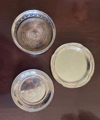 trois assiettes en argent posées les unes à côté des autres sur une table en bois