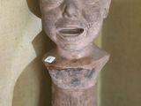 une sculpture en argile représentant un visage, posée sur un socle