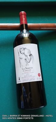 une bouteille de vin posée sur une table de billard, à côté d'une queue de billard