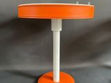 une lampe de table orange avec un pied blanc et un pied noir
