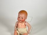 a small baby doll sitting on a clear chair