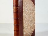 an old book with a brown cover sitting on top of a white table