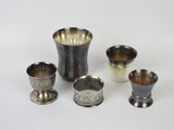 quatre coupes en argent et un vase en argent posés sur un plateau blanc