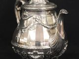 an antique silver teapot with a bird on the lid