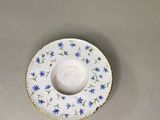 une assiette blanche ornée de fleurs bleues, posée dans un évier