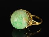a close up of a gold ring with a green stone
