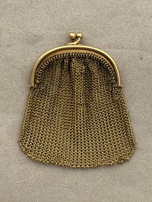 a gold purse with a chain handle on a white surface