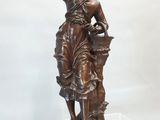 statue en bronze représentant une femme tenant un panier de fleurs, posée sur un socle