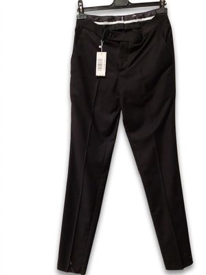Le pantalon noir est suspendu à un cintre accroché à un mur blanc.