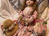 a doll that is sitting on a bed with a hat