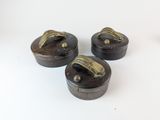 trois petites boîtes en bois munies de poignées métalliques, posées sur une surface blanche