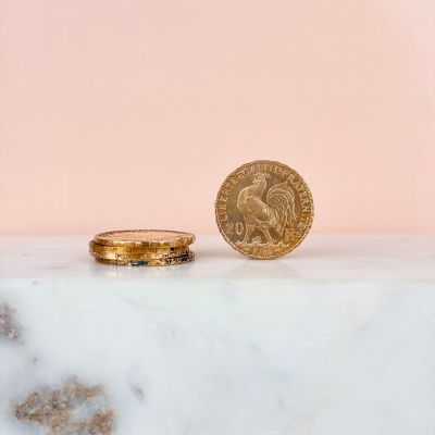 two gold coins sitting next to each other on a marble surface