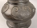 a metal vase with a lid on a white table
