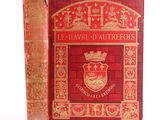 un vieux livre à la couverture rouge posé sur une surface blanche