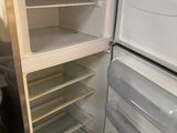 a white refrigerator with its door open next to a trash can