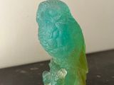 un oiseau vert perché sur une table noire