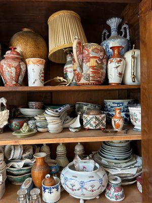 une vitrine en bois sur laquelle sont exposées de nombreuses pièces de poterie de styles variés