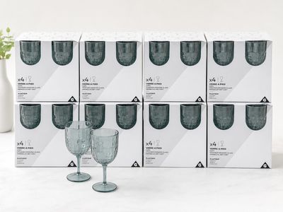 plusieurs verres à vin vides posés sur une table, à côté d'un vase