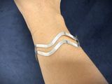 someone is wearing a silver bracelet that has a chevron design on it