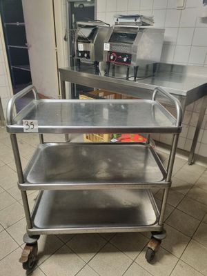 a metal cart with three trays on it in a kitchen