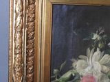 a painting of flowers in a gold frame on a blue wall