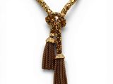 a gold necklace with a tassel on a white background