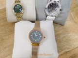 trois montres sont posées sur un coussin, sur une table en bois