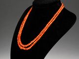 an orange beaded necklace is displayed on a black mannequin