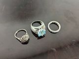 three rings with a blue topaz stone sitting on top of a black surface