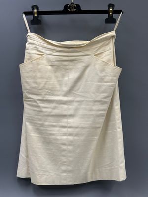 a white skirt hanging on a hanger against a gray wall