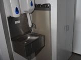 une photo de toilettes publiques avec un lavabo et un sèche-mains