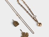 a close up of a gold necklace and two other items on a white surface