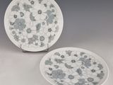 two white and blue plates with flowers on them sitting on a table