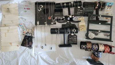 a lot of jewelry on a bed with a white sheet