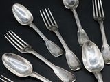 a lot of spoons and forks on a black table