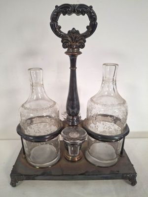 three glass bottles and a metal holder on a table
